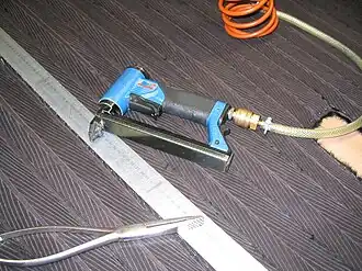 Richten der galonierten Fellbahnen an der Metallschiene, Zweckzange und Pressluftpistole