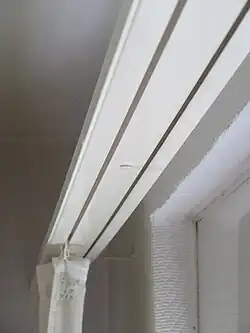 Eine weiße zweiläufige Gardinenschiene mit Gardine