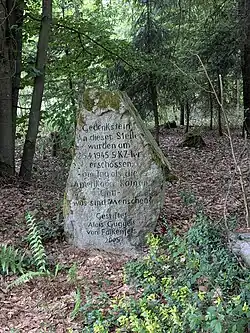 Inschrift: Gedenkstein. An dieser Stelle wurden am 25.4.1945 5 KZ-ler erschossen - am Tag an dem die Amerikaner kamen. Gott - was sind Menschen? Gestiftet Alois Guggeis von Falkenfels 2005