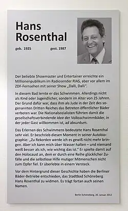 Gedenktafel, die Hans Rosenthal gewidmet ist. Die Tafel ist an einer Wand angebracht und aus Metall gefertigt. Sie enthält einen Text, der Hans Rosenthal als beliebten Showmaster und Entertainer ehrt, bekannt durch die Radiosendung im RIAS und die Fernsehsendung Dalli, Dalli. Ein zentraler Punkt der Inschrift ist, dass Rosenthal erst im Alter von 25 Jahren Schwimmen lernte, da ihm als Jude während des Dritten Reichs der Zutritt zu öffentlichen Schwimmbädern verboten war. Die Tafel beschreibt, wie das Schwimmenlernen für Rosenthal eine symbolische Bedeutung hatte, die er später auf das Überleben des Holocausts bezog. Außerdem wird erwähnt, dass das Stadtbad Schöneberg ihm zu Ehren seinen Namen trägt. Die Tafel ist schlicht gehalten und legt den Fokus auf Rosenthals Geschichte und die Würdigung seiner Leistungen.