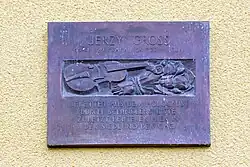 Rechteckige Gedenktafel mit Aufschrift Jerzy Gross; 16.11.1929 Krakau; 27.7.2014 Köln; gerettet aus dem Holocaust durch Schindlers Liste; zuletzt lebte er hier in der Siedlung der GAG