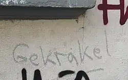 Auf einer Wand steht mit krakeliger Schrift "Gekrakel" geschrieben.