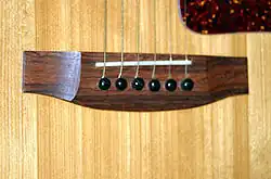 Steg mit integriertem Saitenhalter einer Westerngitarre