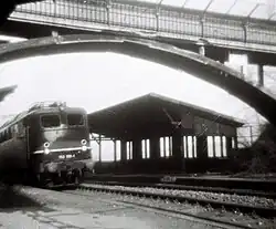 Sommer 1975: der aufgelassene Haltepunkt mit einer E-Lok der Baureihe 150, im Bild die Fußgängerbrücke, die früher als Bahnsteigzugang diente