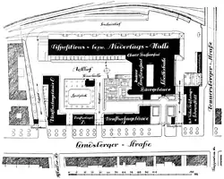 von oben: die Ladegleise, das querstehende Lagerhaus, die Verwaltungsbauten und an der Straße im Süden die Wohnhäuser. Im Südosten die Prüfanstalt