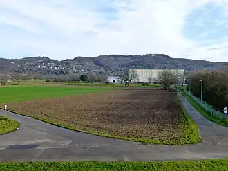 Blick von der Brücke der B 38 über die neue Weschnitz ostwärts zum Hirschkopf: Hirschkopf (mittig rechts hinter der großen Halle), Saukopf (mittig hinter weißem Gebäude), Nächstenbach (Weinheim) (am Hang mittig links); dahinter links oberhalb der Weinheimer Kopf