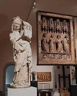 Eine Kalkstein Figur, die Königin Johanna I. von Navarra, Frankreich, mit einem Kapellenmodell in den Händen zeigt. Ausstellungsansicht im Berliner Bode-Museum