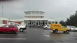 Frontalansicht des Flughafengebäudes mit Parkplatz im Vordergrund