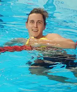 Farbfoto von Cameron McEvoy nach dem Rennen. Nur der Kopf und der linke Oberarm schauen aus dem Wasser, in der linken Hand hält er seine gelbe Bademütze.