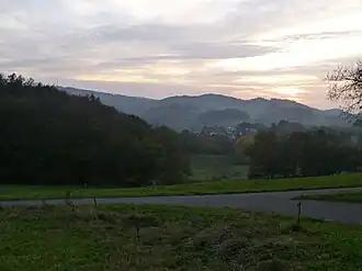 Blick vom Wirtschaftsweg Schleichweg (R9) nordöstlich von Kolmbach westsüdwestwärts zum Knörschhügel: Krehberg (links), Knörschhügel mit Götzischberg (mittig links) und Knodener Kopf (mittig rechts); in der Bildmitte Kolmbach; rechts unterhalb des Knörschhügels ist die Ortschaft Breitenwiesen zu erahnen