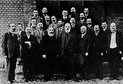Kollegium des Wilhelmsgymnasiums in Königsberg im Jahr 1912. Professor Jäger (Jimbo), Probekandidat Unger, Professor Amoneit (Asaph), Seminarkandidat Schimanski, Professor Bork, Professor Peters, Oberlehrer Cybulla (Schybs), Professor Luther, Direktor Wagner, Vorschullehrer Braun, Professor Stange (Humpel), Oberlehrer Foethke, Professor Lullies, Oberlehrer Dehnen (Barbarossa), Professor Joost, Oberlehrer Kroll, Vorschullehrer Kirbuß, Professor Lanenpusch, Professor Kühn (Audax), Professor Kröhnert, Vorschullehrer Michaelis, Zeichenlehrer Ludat.