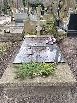 Grab mit aufliegender zweiteiliger beschrifteter Steinplatte auf einem Steinsockel mit Kreuz.