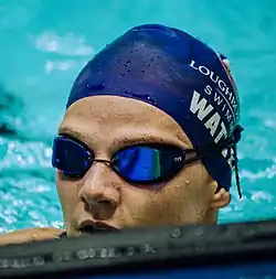 Marie Wattel hat nach einem Rennen noch die Schwimmbrille auf. Die blaue Bademütze trägt in weißer Schrift ihren Nachnamen und den Namen ihrer Universität.