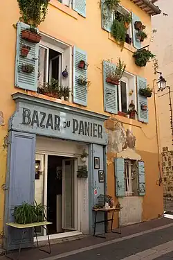 Die mediterrane Außenfassade des Ladens Bazar du Panier mit Fensterläden und Blumenkästen.