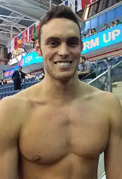 Matteo Rivolta steht mit nacktem Oberkörper vor einer nahezu leeren Tribüne.