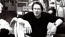 Der Maler Matthias Brock sitzend in seinem Atelier.