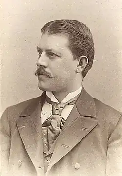 Michael Mayr mit Schnurrbart, breiter Krawatte und dunklem Anzug