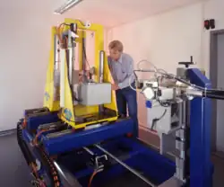 Aufbau einer Mikro-CT-Anlage; im Vordergrund die Röntgenröhre, in der Mitte das Objekt auf einem Drehteller, hinten der Flachbilddetektor