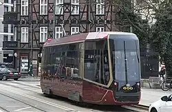 Das Fahrzeug wurde von links hinten fotografiert. Die Fensterbereiche und die Drehgestelle sind schwarz lackiert, der Rest dunkelrot mit einigen goldenen Applikationen. Das Heck wirkt schmal und hat keine Kühlergrill-Attrappe.