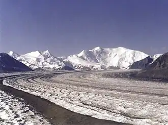 Der Nabesna-Gletscher vor dem Mount Blackburn (Bildmitte), den Atna Peaks (Doppelgipfel links davon) und dem Parka Peak (schneebedeckter Gipfel am linken Bildrand)
