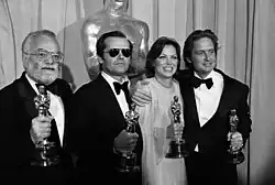 Saul Zaentz, Produzent, Jack Nicholson, Schauspieler, Louise Fletcher, Schauspielerin und Michal Douglas, Produzent halten je einen Oscar-Pokal in der Hand als Auszeichnung ihrer Leistungen für den Film Einer flog über das Kuckucksnest. Halbkörpergruppenporträt, Schwarzweißfoto, Breitformat, Vergrößerung inklusive Perforierung des Kleinbildfilms.