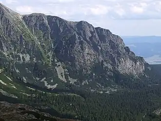 Blick vom oberen Teil des Tals Mengusovská dolina, mit sichtbaren Serpentinen im Zuge des Wanderwegs Tatranská magistrála sowie den Galéria Ostrvy genannten Felswänden rechts