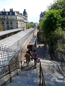 Westliche Fußgängertreppe, auf halber Höhe der Eingang zur Métro