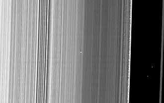 Der helle Punkt mit dem langen Schatten in der Bildmitte ist S/2009 S1. Rechts im Bild die Cassini-Teilung.