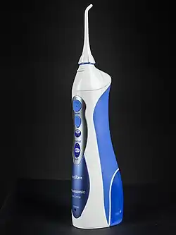 Schrägansicht einer kabellosen Munddusche. Auf der linken Seite sind die Tasten zur Bedienung zu sehen