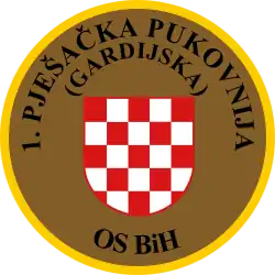 Soldat des 1. Infanterie-(Garde-)Regiments OS BiH (Traditionsregiment HVO) mit seinem Partner von der US-Armee während eines Manövers auf dem Truppenübungsplatz „Eugen Kvaternik“ (2012) und Ärmelabzeichen der Einheit.