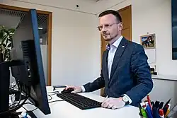 Bezirkstagspräsident Peter Daniel Forster steht an seinem Schreibtisch im Ansbacher Bezirksrathaus und arbeitet. Er schaut auf seinen PC-Bildschirm und hat eine Hand an der Maus.