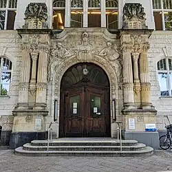 Portal des Volkshochschul-Gebäudes am Barbarossaplatz mit Verzierungen und Athene über dem Eingang
