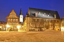 Altes Rathaus und Fachwerkhaus am Marktplatz von Quedlinburg bei Nacht mit beleuchteten Gebäuden und dunklem Himmel