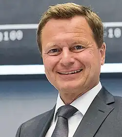 Porträtbild von Raimund Brichta vor der DAX-Tafel an der Frankfurter Börse im Jahr 2015