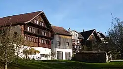 Der flache Giebelbau des Rathauses (links im Bild, Rückseite des Ge­bäudes) hat volumetrisch keine Dominanz im Ort.[1]