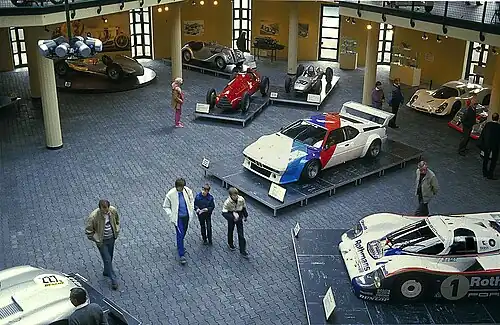 Ausreichend Platz für Fahrzeuge und Be­sucher, rechts Porsche 956, in der Mitte BMW M1, dahinter Alfa Romeo Tipo 159 und Porsche F1-804