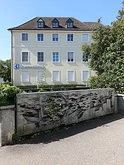 Reliefplastik. Kommunikation 1972. Von Franco Annoni (1924–1992) Bildhauer. Magdenerbach, Kaiserstrasse 6, Postgebäude in Rheinfelden (AG). 470 × 130 × 30 cm. Wachsausschmelztechnik, Guss nach dem Cire-perdue-Verfahren. Material Peraluman. Gestiftet von der Schweizer Eidgenossenschaft.