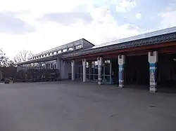 Gezeigt ist ein einstöckiges Schulgebäude von außen. Auf dem Dach befindet sich eine Photovoltaik-Anlage.