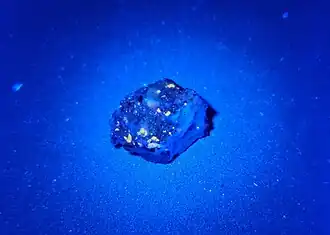 Fluoreszierender „Ribbeck“-Meteorit im UV-Licht mit λ = 365 nm (Probe AKM03C)