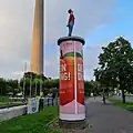 Litfaßsäule mit einer der „Säulenheiligen“ von Christoph Pöggeler (Düsseldorf, ab 2001)