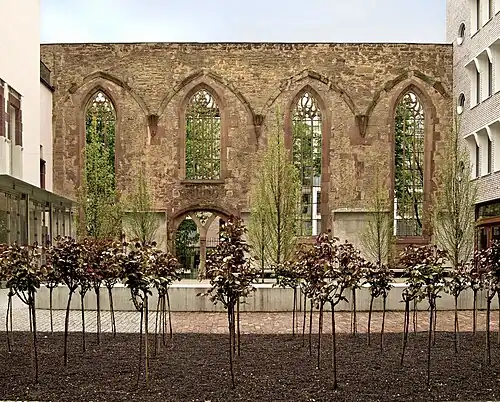 Vier der fünf erhaltenen Wandfelder der Südfassade, vom Innenhof des Hospitalhofs aus gesehen (2017). Das Denkmal liegt hinter dem linken Spitzbogenfenster.