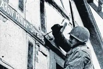 US-Soldat entfernt Straßenschild. 1945