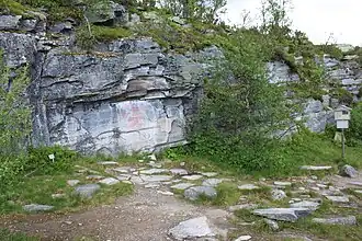 Malereien der Felswand mit Hinweisschild