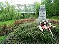 Gedenkstein von 2007 mit neuer Tafel aus 2012 im Jahr 2019, ehemalige Krakau-Oberschlesische Eisenbahn im Hintergrund