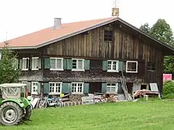 zweigeschossiger, verschindelter Blockbau mit flachem Satteldach, zum Teil Schubflügelfenstern und Klebdächern
