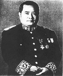 Mann im mittleren Alter ab Becken in rechtsseitig ordenbehängter Militäruniform von vorn in die Kamera schauendin schwarzweiß.