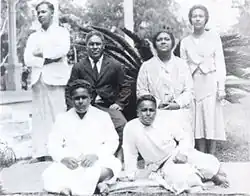 Die königliche Familie von Tonga um 1930. Schwarz-Weiß-Aufnahme von sechs Personen vor einem Palmfarn. Stehend im Hintergrund: Prinz Taufa’ahau und die Schwester der Königin Prinzessin Fusipala; in der Mitte sitzend Prinz Tungī und Königin Sālote. Im Vordergrund auf dem Boden: Prinz Sione und Prinz Tuku’aho. Alle in hellen Kleidern außer Prinz Tungi im schwarzen Anzug mit Krawatte.