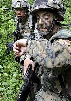 Soldat des 1. Infanterie-(Garde-)Regiments OS BiH (Traditionsregiment HVO) mit seinem Partner von der US-Armee während eines Manövers auf dem Truppenübungsplatz „Eugen Kvaternik“ (2012) und Ärmelabzeichen der Einheit.