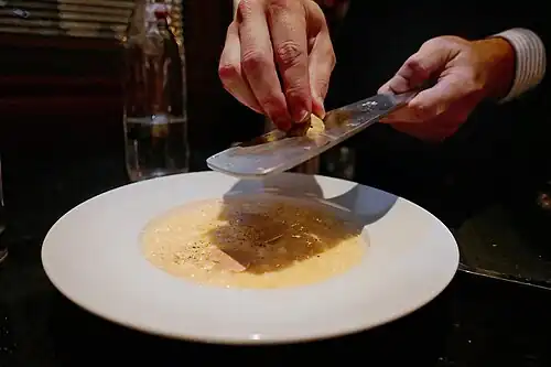 Garnierung eines Risottos mit hauchdünnen Trüffel­scheiben, mit Hilfe eines Trüffel­hobels