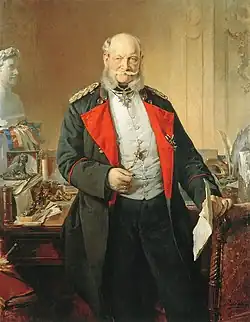 Die 1883 entstandene Ansicht zeigt Wilhelm im Arbeitszimmer des Alten Palais in Berlin. In der linken Hand hält er ein Schriftdokument, in der rechten einen Zwicker. Im Hintergrund ist sein mit Schreibutensilien und persönlichen Gegenständen voll gestellter Schreibtisch zu sehen. Die Szene suggeriert, dass Wilhelm seine Arbeit gerade erst eingestellt hat, um einen Gast – in diesem Fall den Bildbetrachter – zu empfangen.[220] Wilhelm I. in seinem Arbeitszimmer, Hofmaler Paul Bülow, 1883 entstanden, Ausstellungsort unbekannt